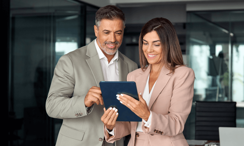 Two people smiling at a tablet.