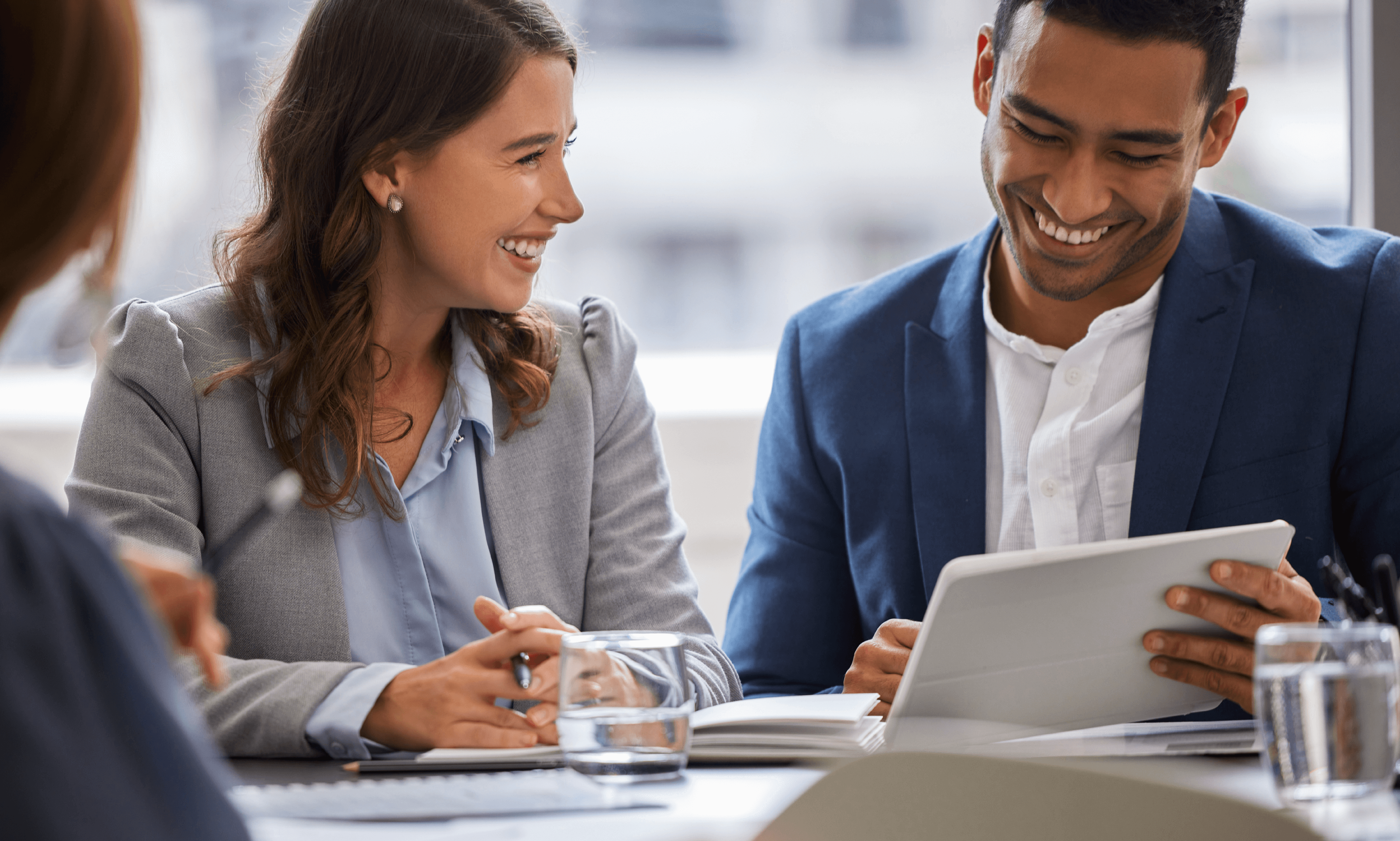 Two people smiling while discussing the content on a tablet.